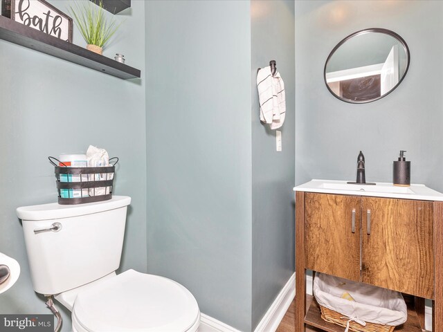 half bathroom featuring baseboards, vanity, and toilet