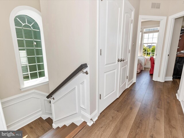 hall featuring wood finished floors, visible vents, and stairs