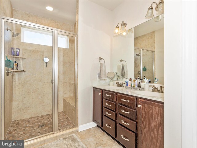 full bath with double vanity, tile patterned flooring, a stall shower, and a sink