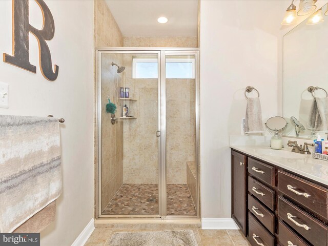 full bath featuring tile patterned floors, vanity, baseboards, and a shower stall