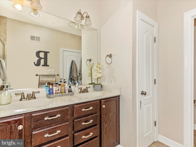 full bath with a sink, visible vents, and double vanity