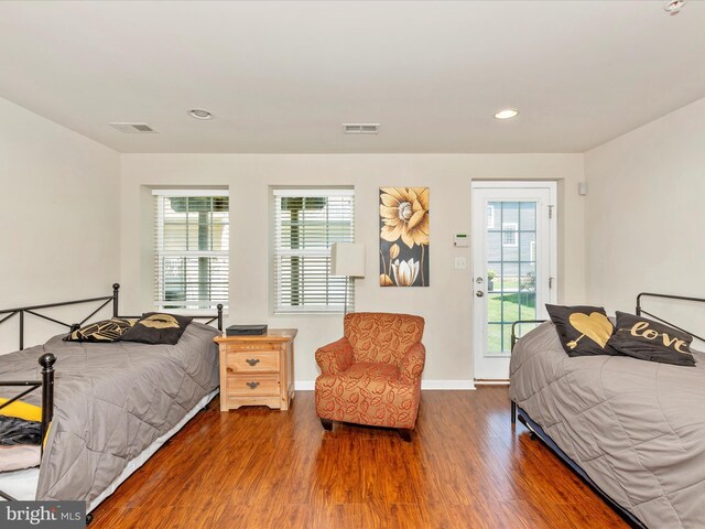 bedroom with wood finished floors, visible vents, and multiple windows