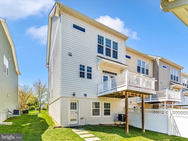 rear view of property featuring fence, a wooden deck, a yard, and central AC