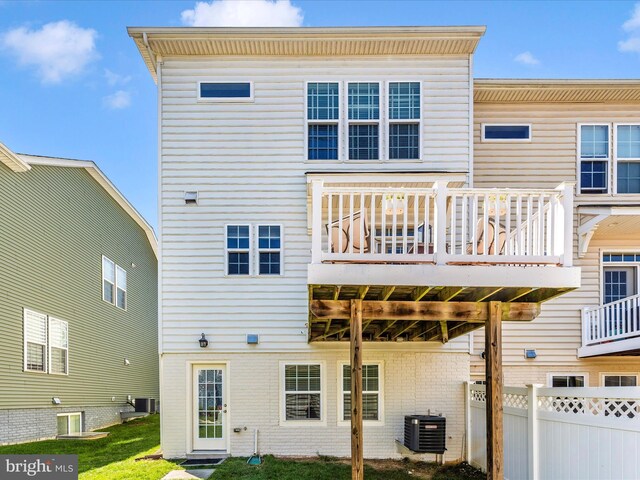 rear view of property featuring central AC, fence, a deck, and a lawn