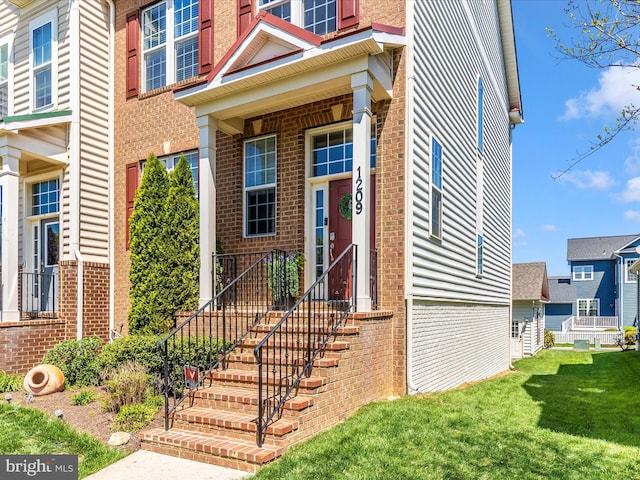 doorway to property with brick siding and a yard
