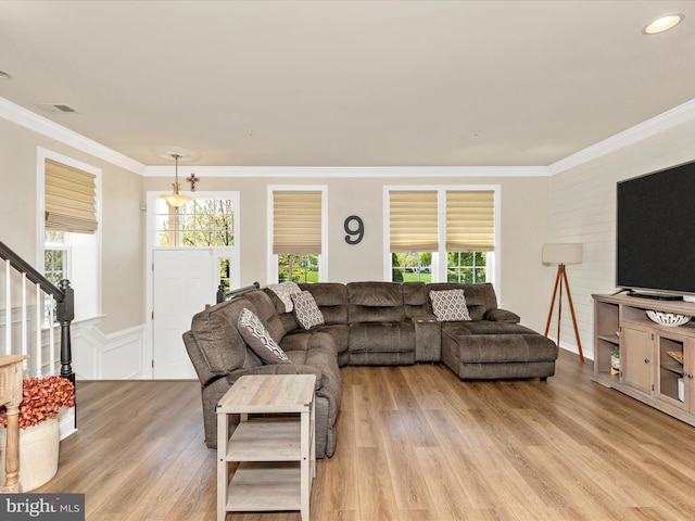 living room with stairs, wainscoting, light wood-style flooring, ornamental molding, and visible vents
