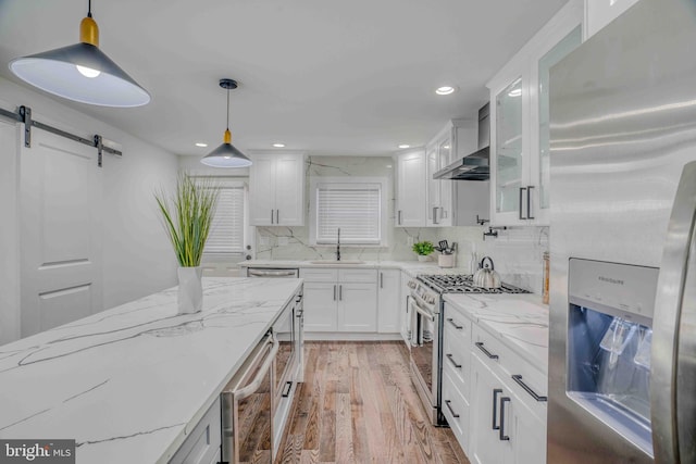 2832 Edgemont St, Philadelphia, PA 19134 - kitchen featuring a barn door, a sink, light wood-style floors, stainless steel appliances, and white cabinetry