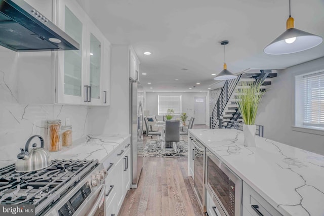 2832 Edgemont St, Philadelphia, PA 19134 - kitchen with white cabinets, exhaust hood, light wood-style floors, glass insert cabinets, and appliances with stainless steel finishes