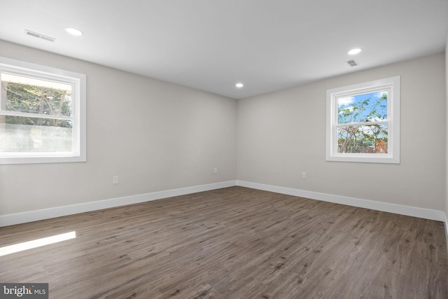 spare room with visible vents, baseboards, plenty of natural light, and wood finished floors