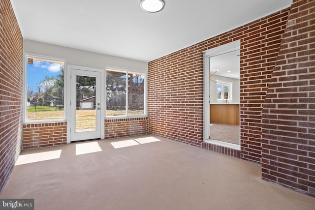 interior space with plenty of natural light, carpet, and brick wall