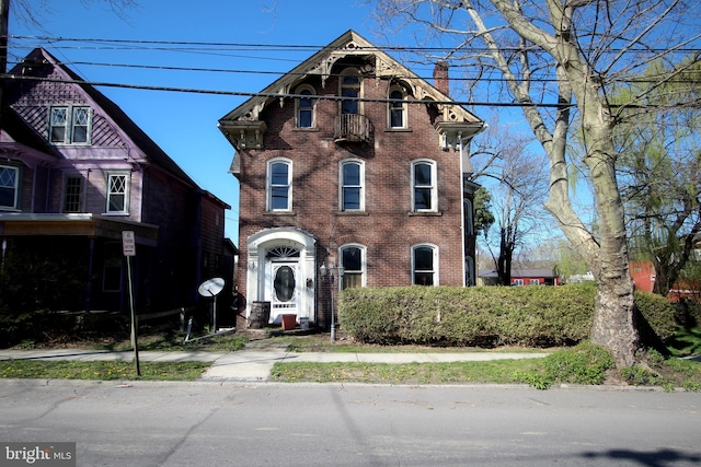 italianate home featuring a chimney and brick siding