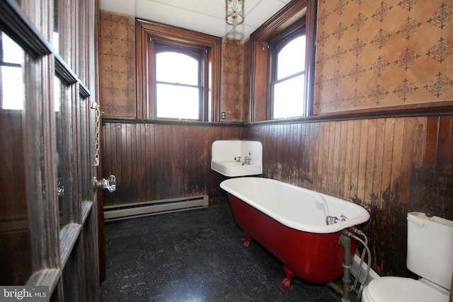 full bathroom featuring wallpapered walls, a freestanding bath, toilet, wainscoting, and a baseboard radiator