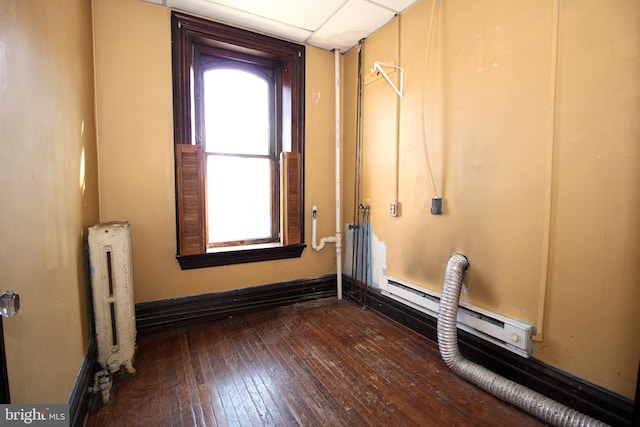 spare room featuring hardwood / wood-style flooring, a baseboard radiator, baseboards, and radiator heating unit