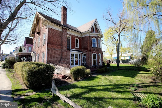 view of home's exterior with brick siding, a yard, and a chimney