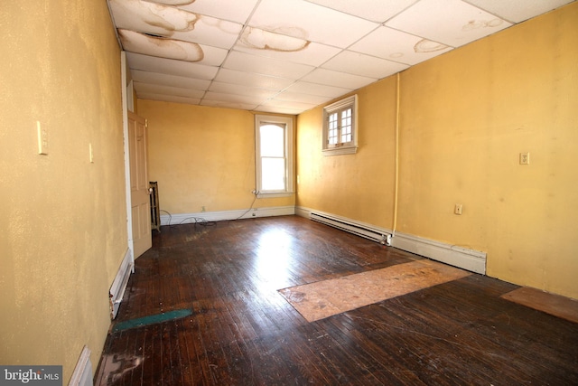 spare room with hardwood / wood-style floors, baseboards, a baseboard radiator, and a drop ceiling