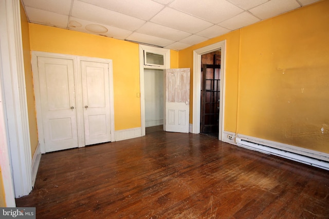 unfurnished bedroom featuring wood-type flooring, a paneled ceiling, baseboards, and baseboard heating