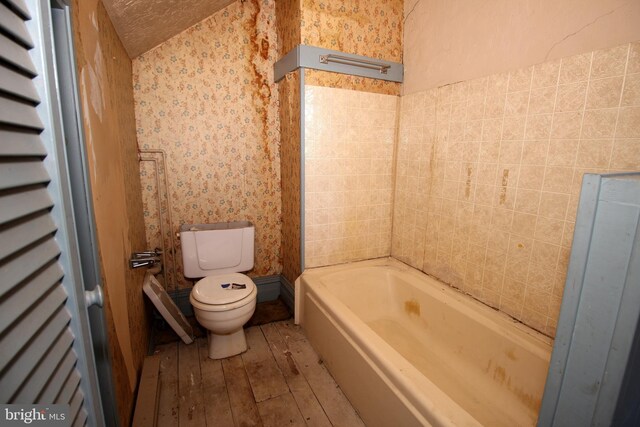 bathroom featuring wallpapered walls, hardwood / wood-style flooring, a bathtub, and toilet