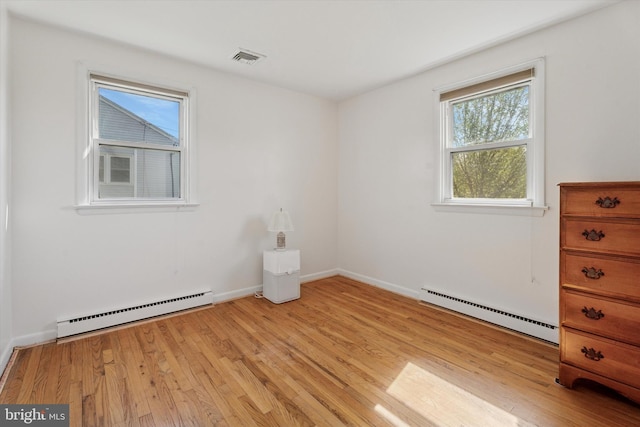 unfurnished room with baseboards, a baseboard heating unit, light wood-style flooring, and visible vents