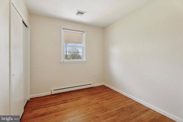 unfurnished bedroom featuring visible vents, a closet, light wood-style floors, baseboards, and a baseboard radiator