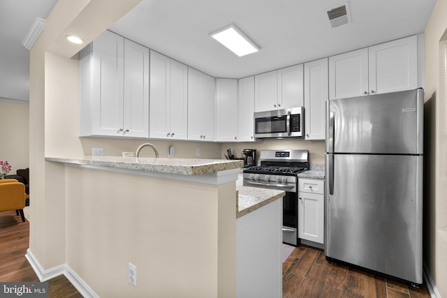 kitchen with appliances with stainless steel finishes, light stone countertops, dark wood finished floors, and visible vents
