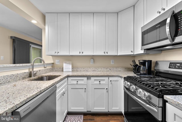 kitchen featuring dark wood-style flooring, light stone countertops, a sink, white cabinets, and stainless steel appliances