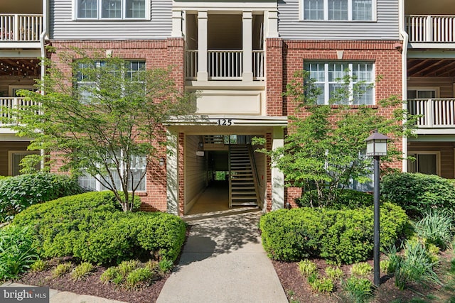 entrance to property with brick siding and a balcony