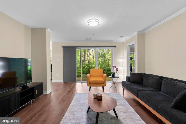 living room featuring crown molding, baseboards, and wood finished floors