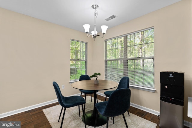 dining space with a notable chandelier, visible vents, baseboards, and wood finished floors