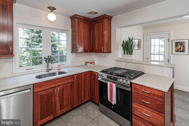 kitchen with a sink, decorative backsplash, appliances with stainless steel finishes, and light countertops