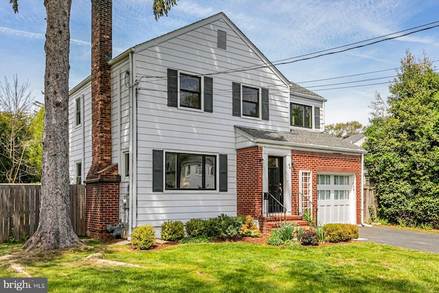 traditional-style house featuring fence, a front yard, brick siding, and aphalt driveway