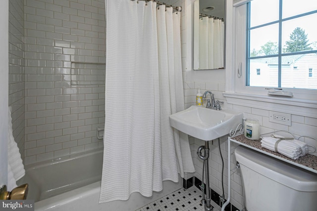 bathroom featuring tile patterned flooring, shower / bath combination with curtain, toilet, tile walls, and a sink