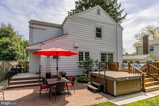 rear view of house with a deck, a patio area, a hot tub, fence, and outdoor dining space