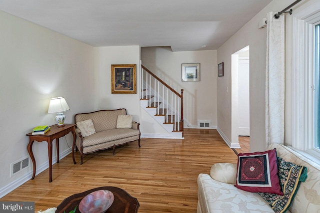 living room with light wood-style floors, baseboards, stairway, and visible vents