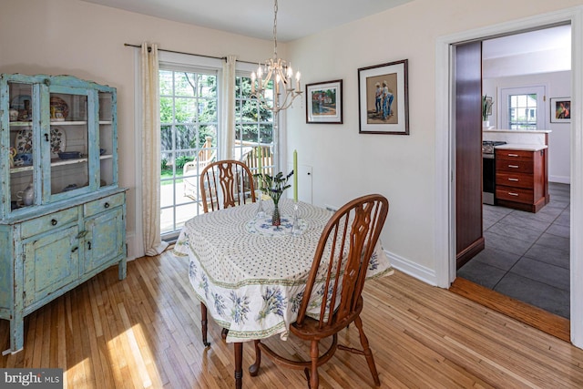 dining area featuring an inviting chandelier, baseboards, and light wood finished floors