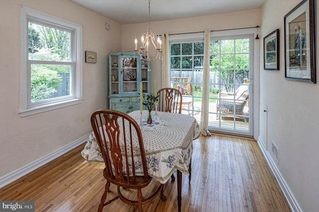 dining space with baseboards, light wood-style flooring, a notable chandelier, and a healthy amount of sunlight
