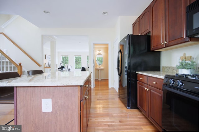 15648 Avocet Loop, Woodbridge, VA 22191 - kitchen with a kitchen island, a breakfast bar area, light wood-type flooring, light stone counters, and black appliances