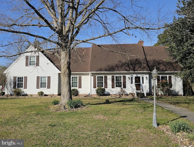 view of front of property with a front lawn, roof with shingles, and a chimney