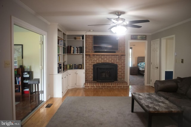 living area with visible vents, ornamental molding, light wood finished floors, and ceiling fan