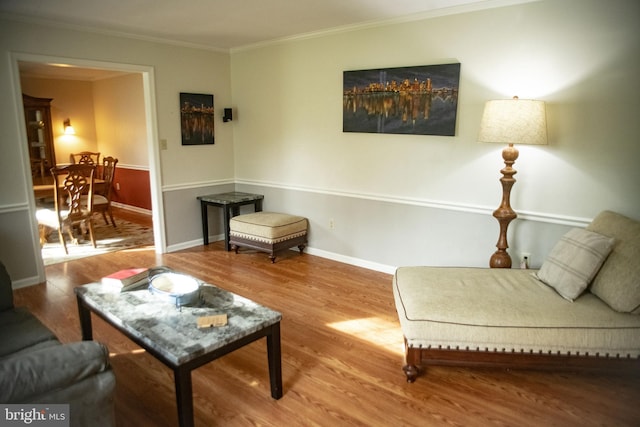 living area featuring crown molding, baseboards, and wood finished floors
