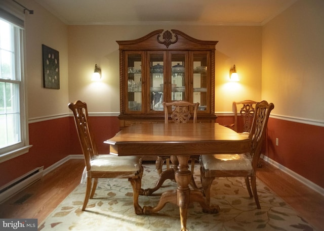 dining space with baseboards, a baseboard radiator, wood finished floors, and a wealth of natural light