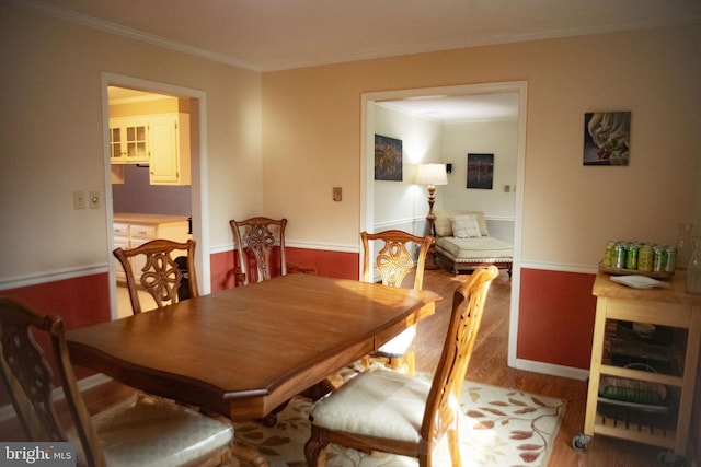 dining area with baseboards, ornamental molding, and wood finished floors