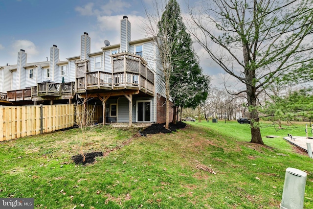 rear view of house featuring a yard, a chimney, fence, and a deck