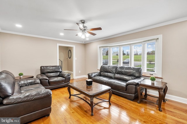 living room featuring crown molding, light wood-style flooring, a ceiling fan, and baseboards