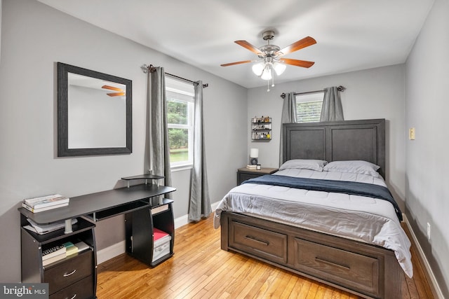 bedroom featuring light wood-style flooring, baseboards, ceiling fan, and multiple windows