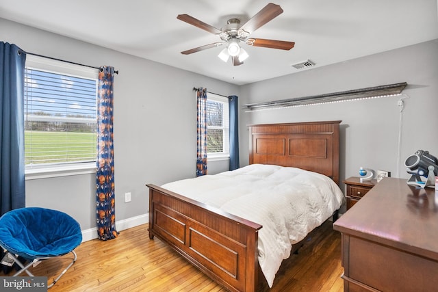 bedroom featuring light wood-type flooring, visible vents, baseboards, and ceiling fan