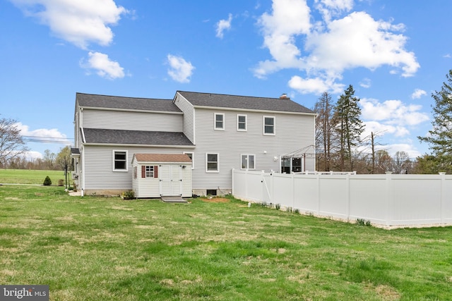 rear view of house featuring a yard and fence