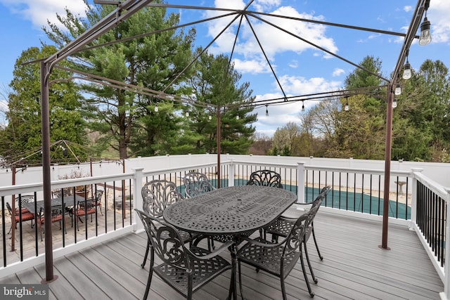 wooden terrace with outdoor dining area, a fenced in pool, and a fenced backyard