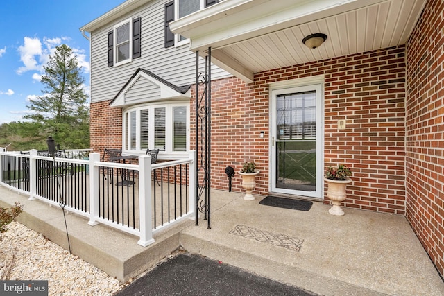 view of exterior entry featuring a patio area and brick siding