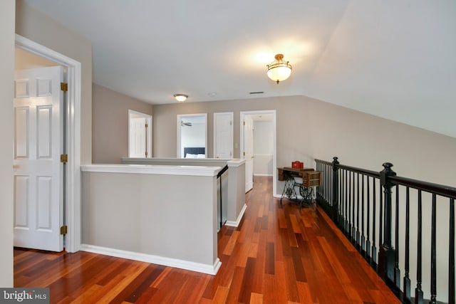 hallway with visible vents, baseboards, wood finished floors, and an upstairs landing