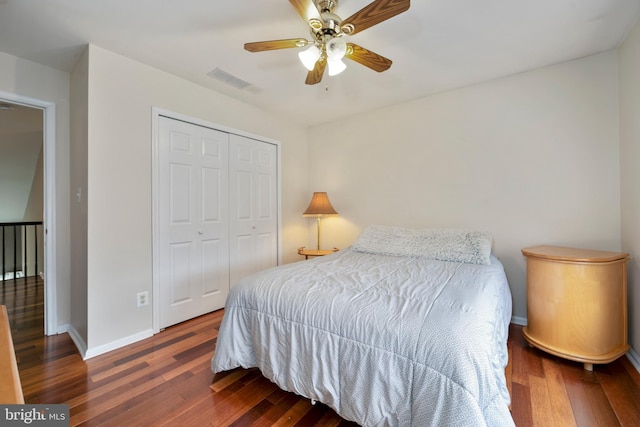 bedroom with visible vents, baseboards, wood finished floors, and a closet
